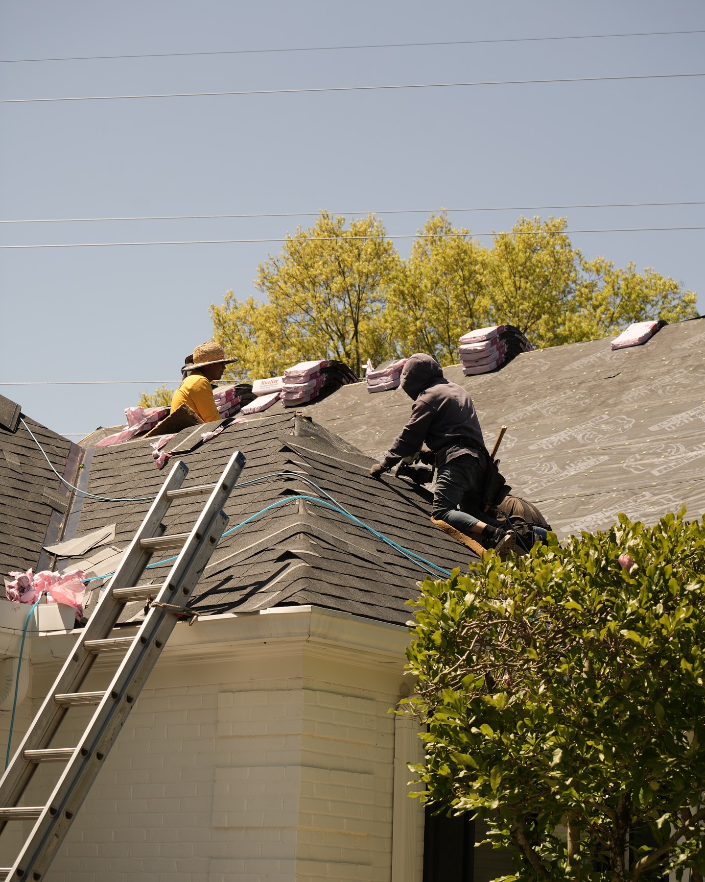crew loading shingle bundles on roof ladder tearoff